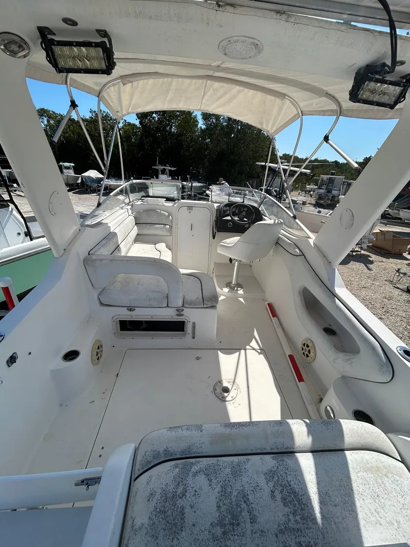 Slide: The Image of 2002 Wellcraft 2400 Martinique boat interior with seating and steering wheel, docked outdoors. - 2