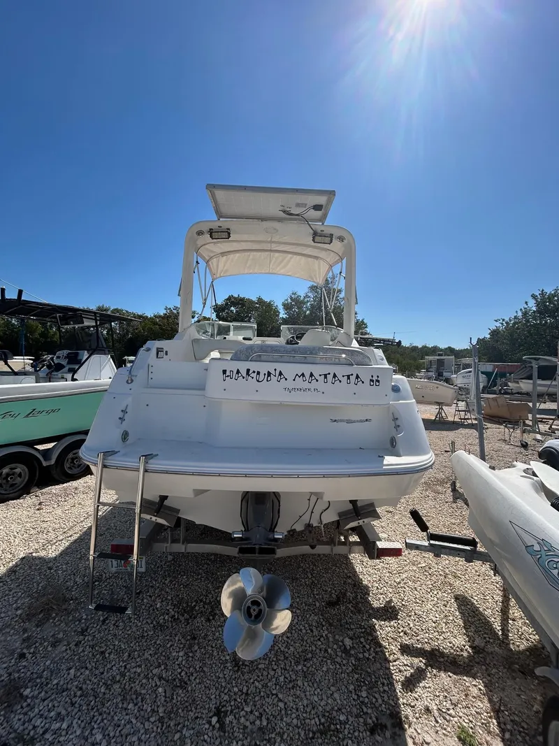 Slide: The Image of 2002 Wellcraft 2400 Martinique boat, rear view, parked on gravel under clear blue sky. - 3