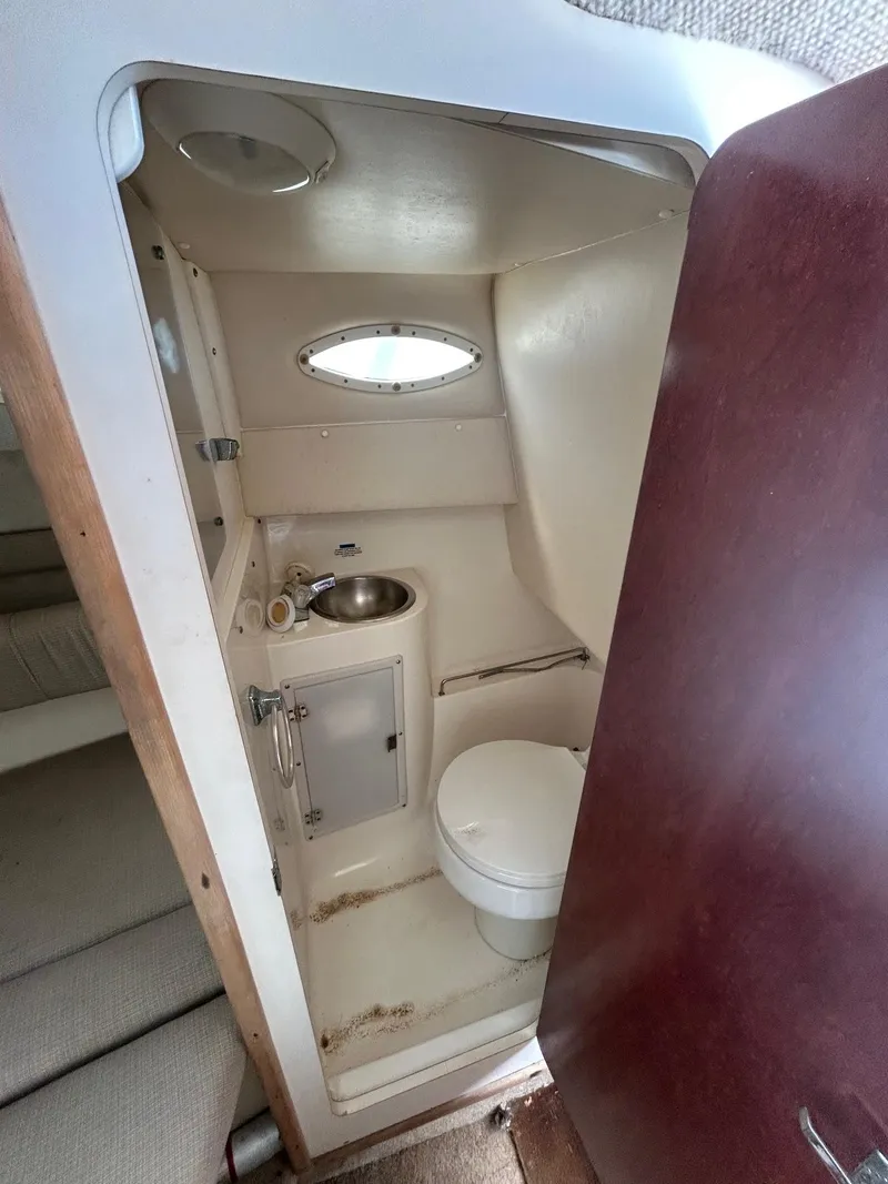 Slide: The Image of 2002 Wellcraft 2400 Martinique boat bathroom with sink, toilet, and oval window. - 5