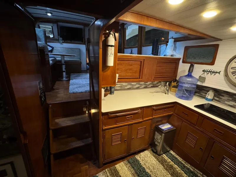 Slide: The Image of 1983 Marine Trader 44 Sundeck interior with wooden cabinetry and compact kitchen area. - 14