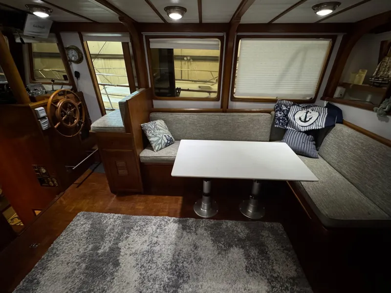 Slide: The Image of 1983 Marine Trader 44 Sundeck interior with cozy seating, table, and nautical decor. - 16