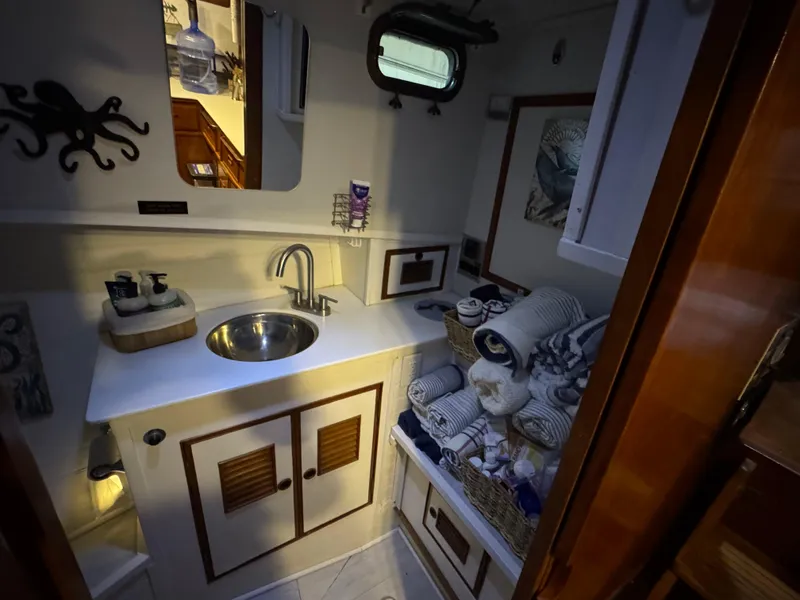 Slide: The Image of 1983 Marine Trader 44 Sundeck bathroom with sink, mirror, and storage cabinets. - 18