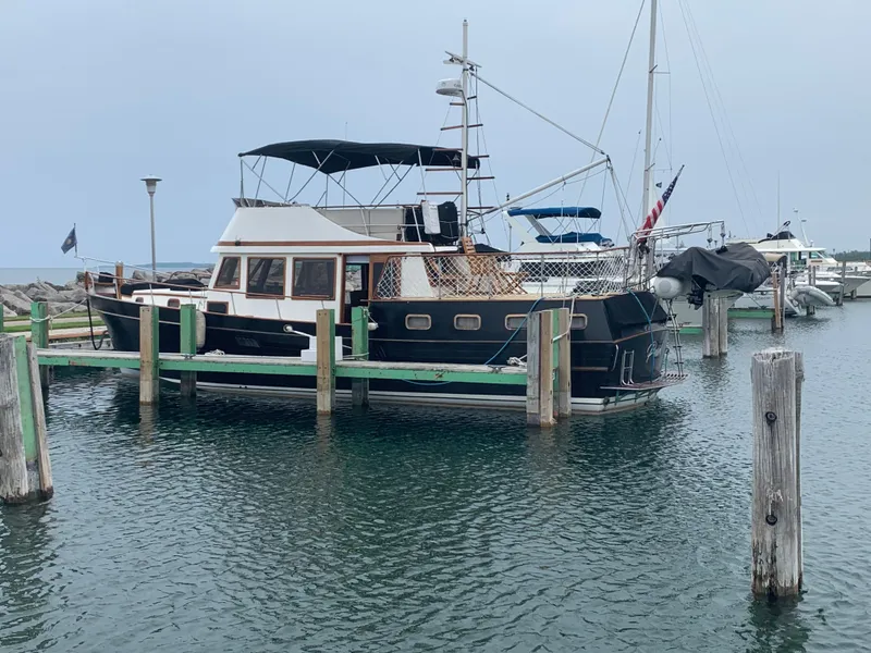 Slide: The Image of 1983 Marine Trader 44 Sundeck yacht docked at marina, featuring classic design and spacious sundeck. - 2