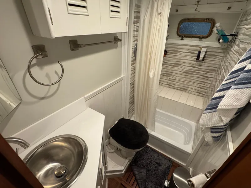 Slide: The Image of 1983 Marine Trader 44 Sundeck bathroom with sink, toilet, and shower, featuring nautical decor. - 22