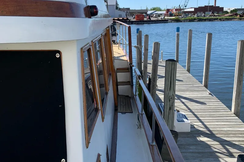 Slide: The Image of 1983 Marine Trader 44 Sundeck docked by a wooden pier on a sunny day. - 6