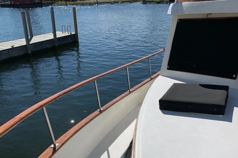 Slide: The Image of 1983 Marine Trader 44 Sundeck yacht on calm water near a dock. - 7