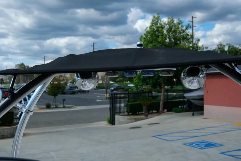 Slide: The Image of Four Winns 220H 2010 boat canopy with lights, parked outdoors under cloudy sky. - 17