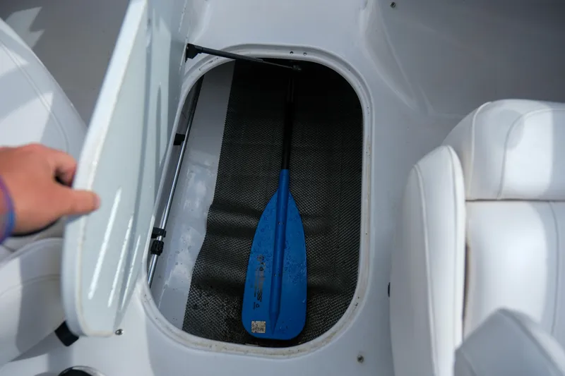 Slide: The Image of Open storage compartment in 2010 Four Winns 220H boat with blue paddle inside. - 19