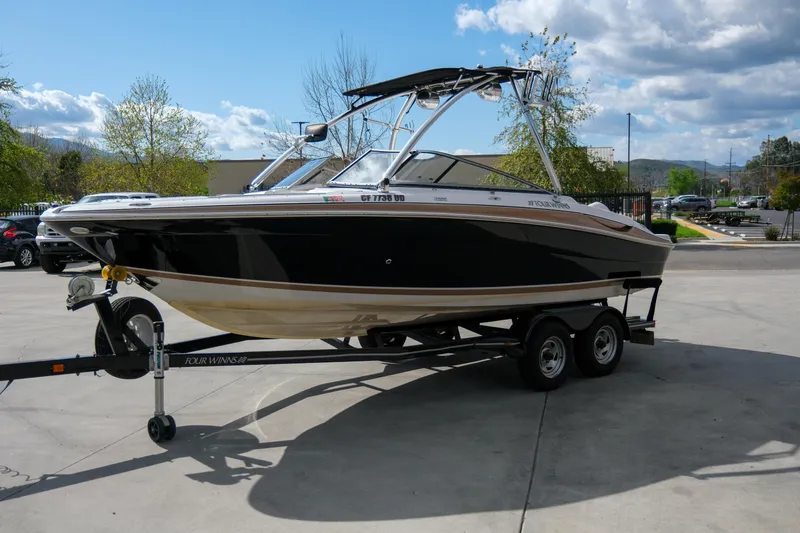 Slide: The Image of 2010 Four Winns 220H boat on trailer, parked outdoors under a partly cloudy sky. - 3