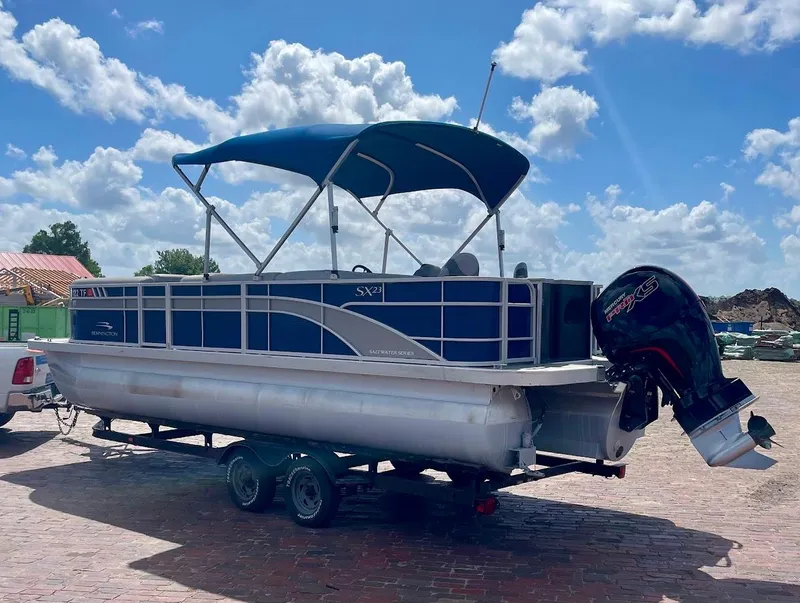 Slide: The Image of 2022 Bennington SX 23 Fishing pontoon boat with canopy on trailer, under a blue sky. - 6