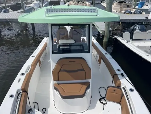 Slide: The Image of 2025 Sea Pro 242 Center Console boat docked, featuring tan seating and a green canopy. - 13