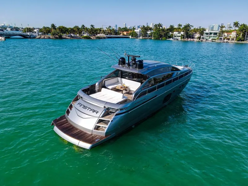 The Image of Luxurious 2014 Pershing 62 yacht cruising on turquoise waters near a tropical shoreline. - 0