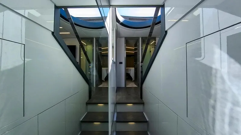 Slide: The Image of Interior of 2014 Pershing 62 yacht, featuring sleek modern design and illuminated stairs. - 13