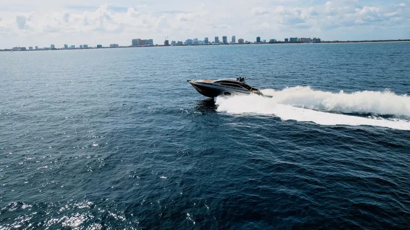 Slide: The Image of 2014 Pershing 62 yacht cruising on open water with city skyline in background. - 9