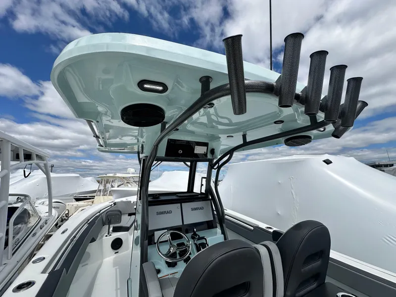 Slide: The Image of 2025 Sea Pro 292 Offshore boat interior with helm, rod holders, and seating under a blue sky. - 23