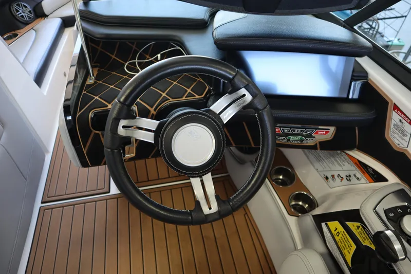 Slide: The Image of 2020 Nautique Super Air Nautique 230 steering wheel and dashboard, featuring modern controls and wood accents. - 17