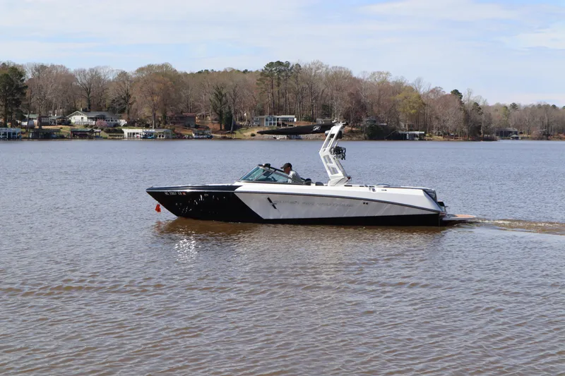 Slide: The Image of 2020 Nautique Super Air Nautique 230 boat cruising on a calm lake. - 2