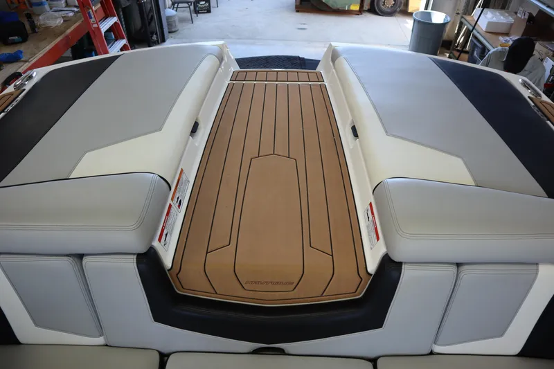 Slide: The Image of 2020 Nautique Super Air Nautique 230 boat interior with cushioned seating and teak-style flooring. - 23