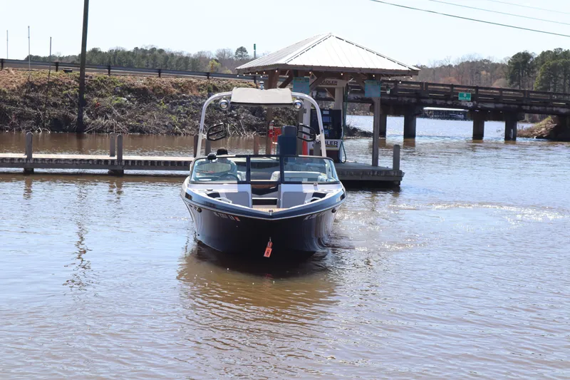 Slide: The Image of 2020 Nautique Super Air Nautique 230 boat docked on a calm river. - 3