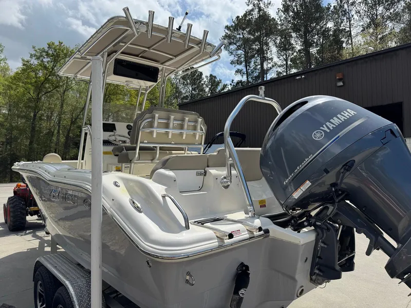 Slide: The Image of 2022 Key West 219 FS boat with Yamaha engine, parked outdoors near trees and a building. - 4