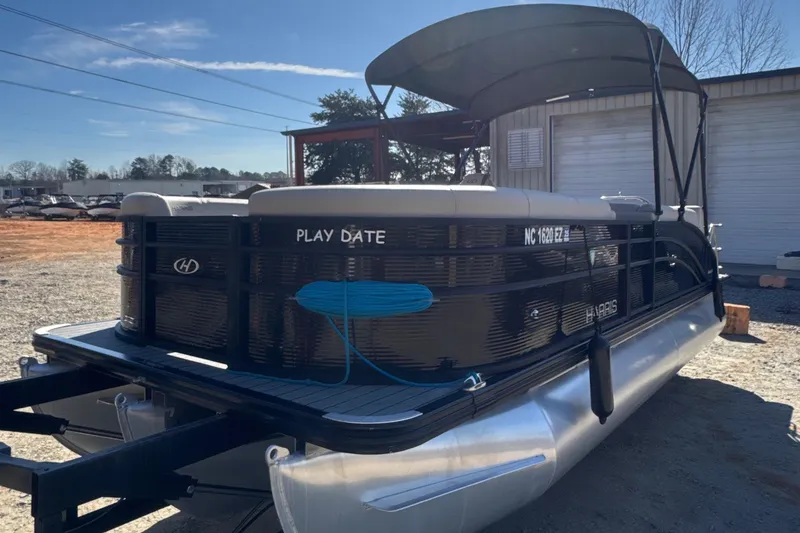 Slide: The Image of 2023 Harris HCX230 SL pontoon boat with canopy, parked outdoors on a sunny day. - 0