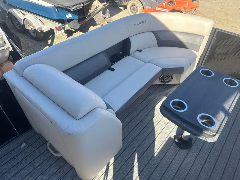 Slide: The Image of 2023 Harris HCX230 SL boat interior with gray seating and table, featuring cup holders. - 13
