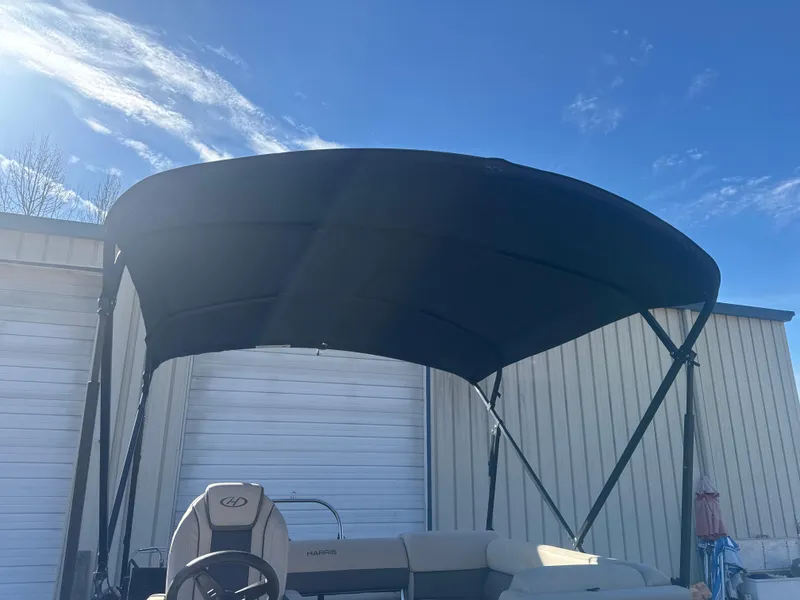 Slide: The Image of 2023 Harris HCX230 SL boat with canopy against blue sky. - 16