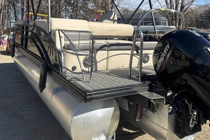 Slide: The Image of 2023 Harris HCX230 SL pontoon boat with Mercury outboard motor, docked on a sunny day. - 2