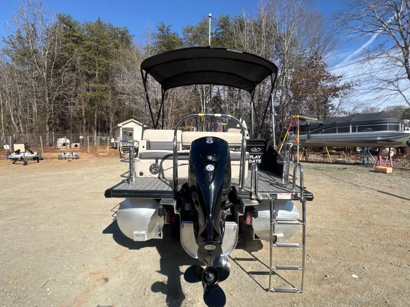 Slide: The Image of 2023 Harris HCX230 SL pontoon boat with canopy and outboard motor, parked on gravel. - 5