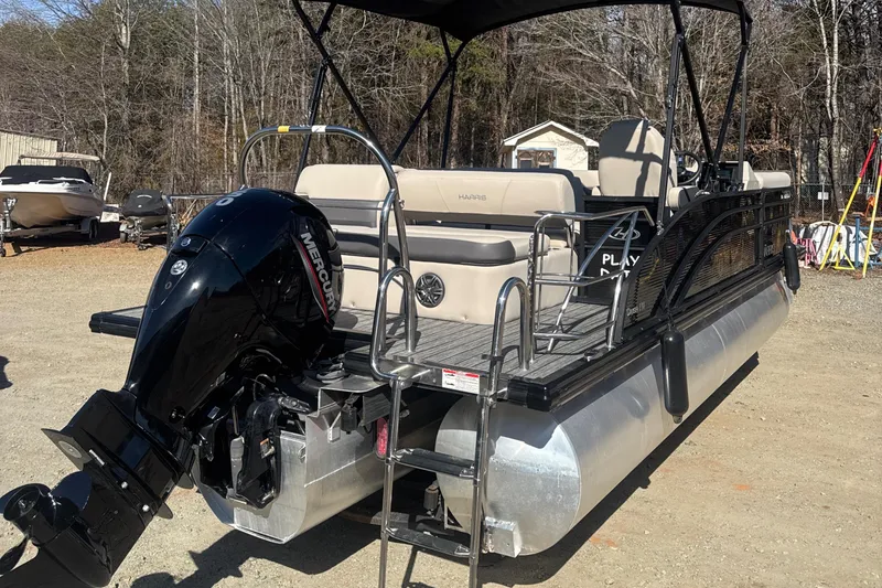 Slide: The Image of 2023 Harris HCX230 SL pontoon boat with Mercury outboard motor, parked on gravel. - 6