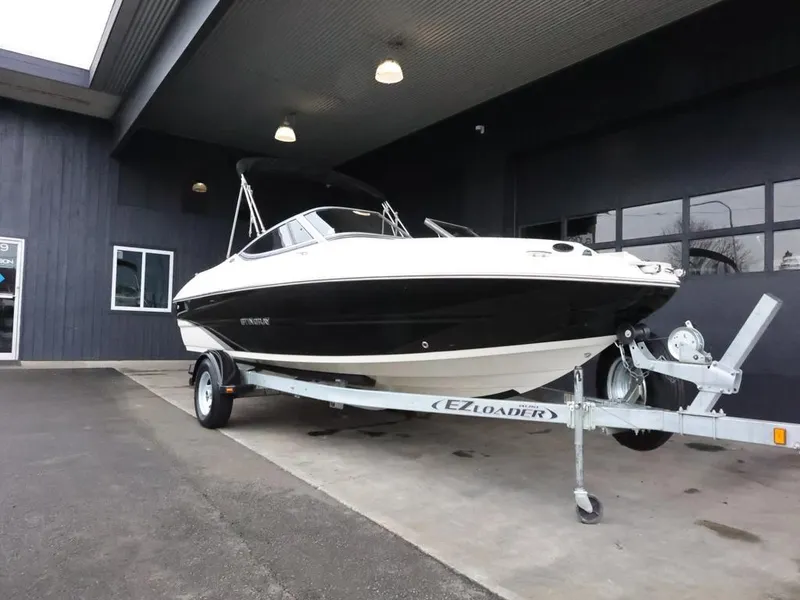 Slide: The Image of 2015 Stingray 198LX boat on trailer outside a building, black and white design. - 2