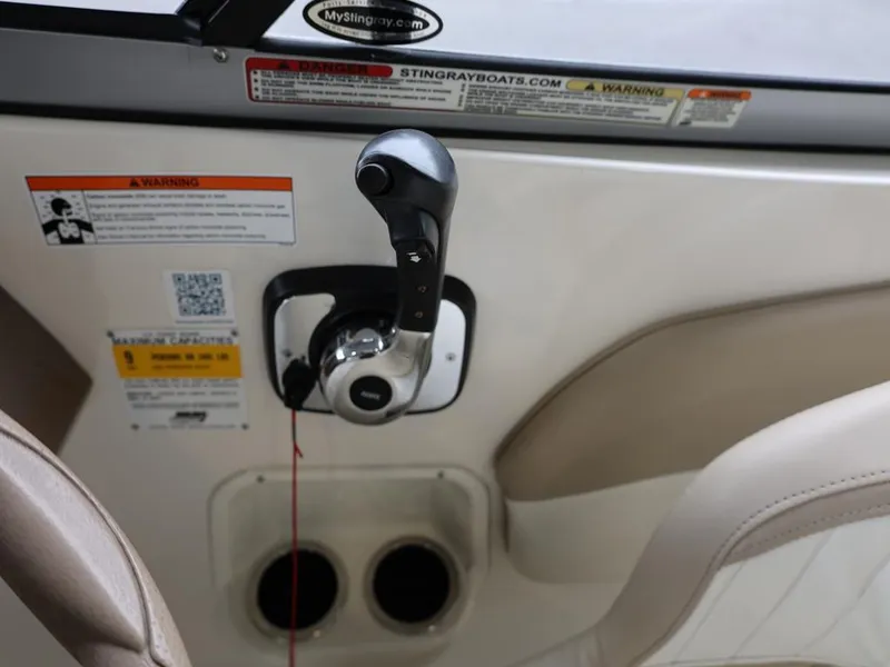 Slide: The Image of 2015 Stingray 198LX boat throttle control with warning labels and cup holders. - 27