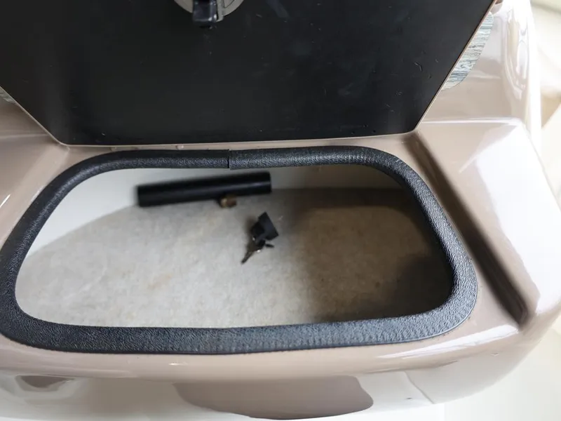 Slide: The Image of Storage compartment of a 2015 Stingray 198LX boat, featuring keys and a small item inside. - 32