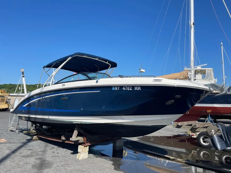 The Image of 2016 Sea Ray 290 Sundeck boat on dry dock, blue hull, with canopy, clear sky background. - 0