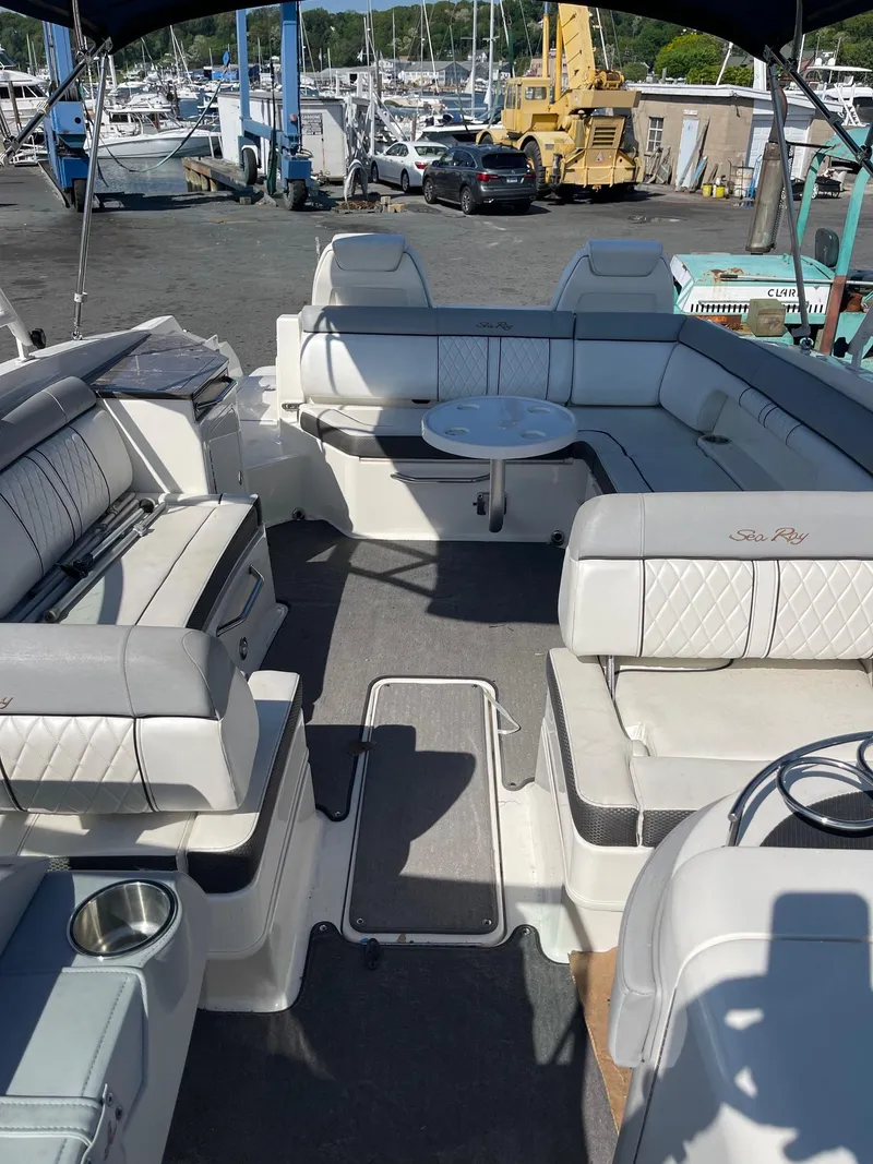 Slide: The Image of 2016 Sea Ray 290 Sundeck interior with spacious seating and table, docked at marina. - 14