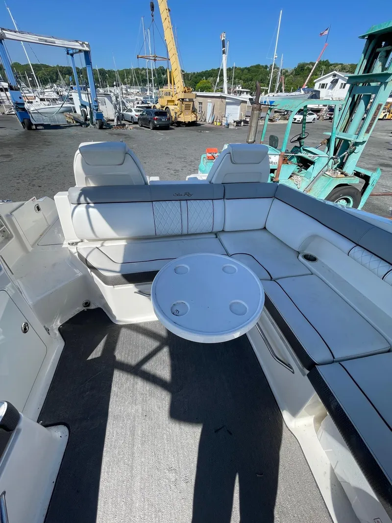 Slide: The Image of 2016 Sea Ray 290 Sundeck interior with white seating and round table, dockside view. - 16