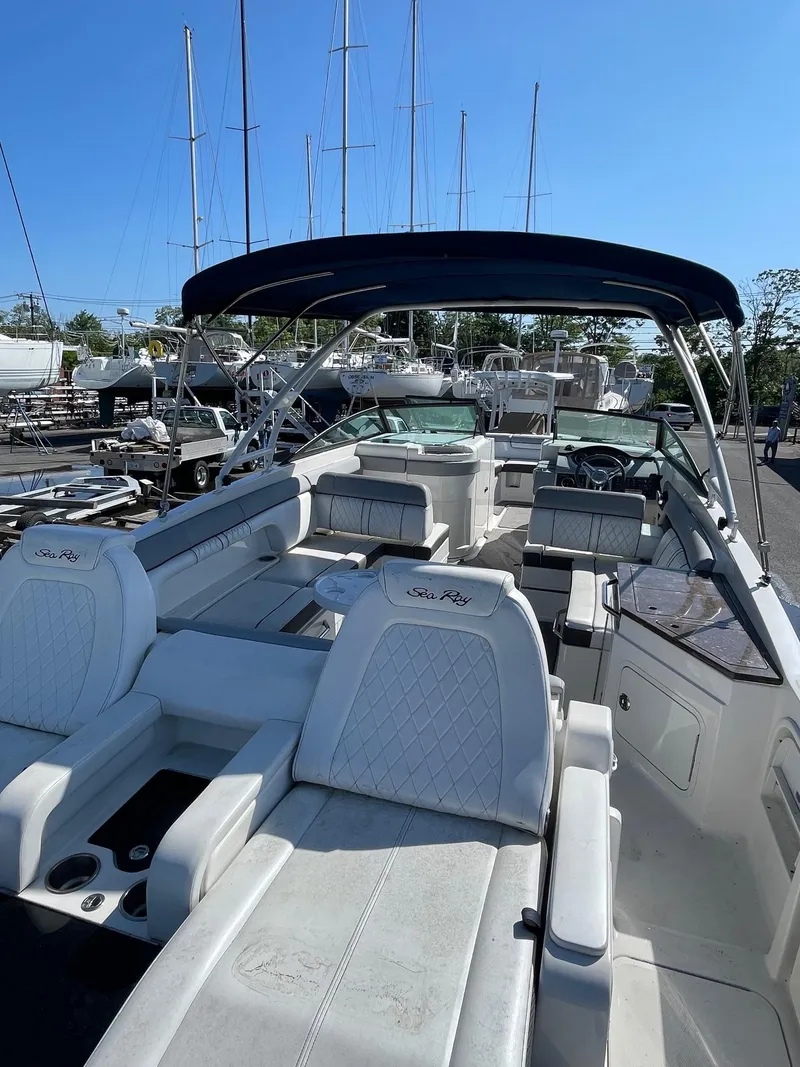 Slide: The Image of 2016 Sea Ray 290 Sundeck boat with spacious seating and canopy, docked under clear skies. - 6