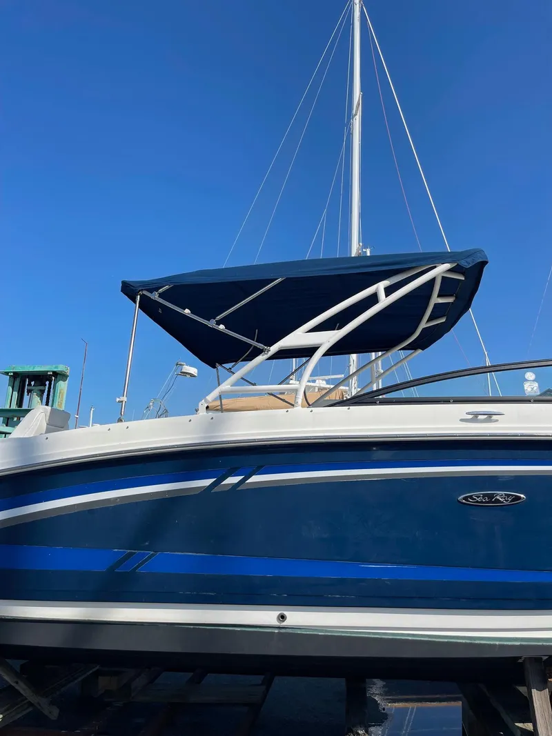Slide: The Image of 2016 Sea Ray 290 Sundeck boat with blue hull and canopy, docked under clear sky. - 7