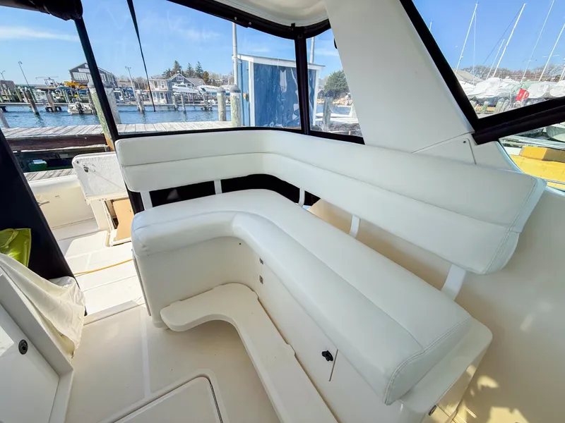 Slide: The Image of 2002 Tiara Yachts 3500 Open Hardtop interior with white seating and marina view. - 11