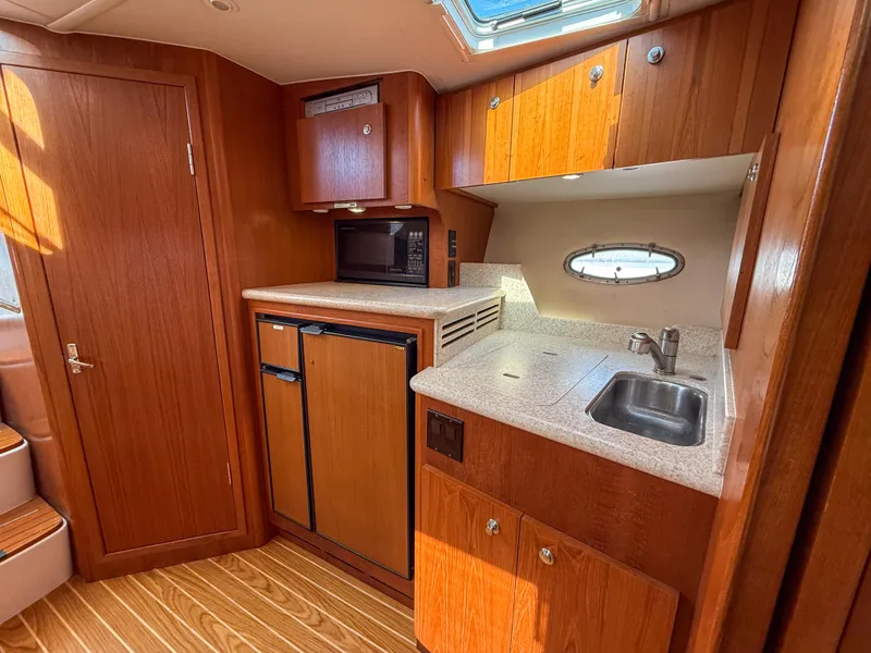 Slide: The Image of 2002 Tiara Yachts 3500 Open Hardtop interior kitchen with wood cabinetry and compact appliances. - 26