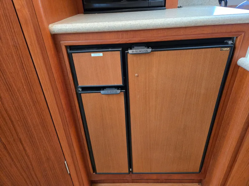 Slide: The Image of 2002 Tiara Yachts 3500 Open Hardtop galley with built-in wooden panel refrigerator. - 28