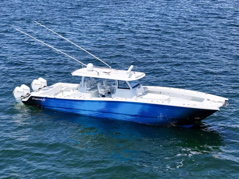 Slide: The Image of 2023 Freeman 47 boat on open water, featuring sleek blue and white design. - 12