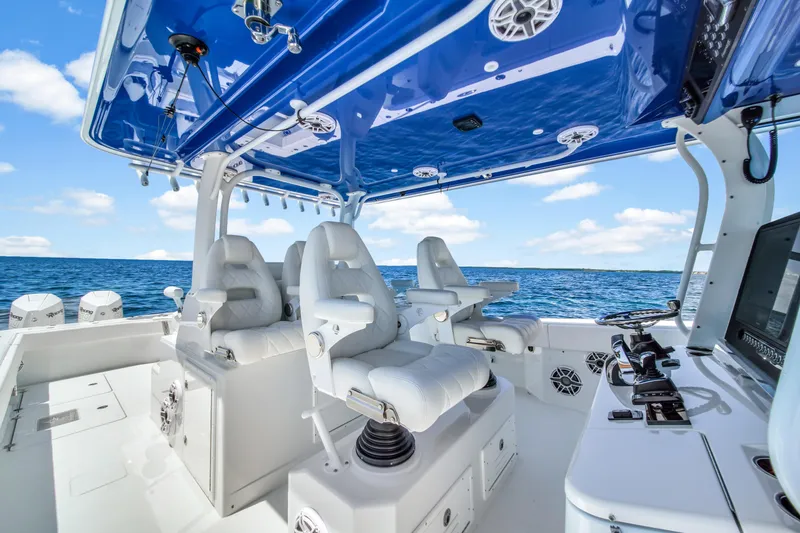 Slide: The Image of 2023 Freeman 47 boat interior with white seats and blue canopy on open water. - 36
