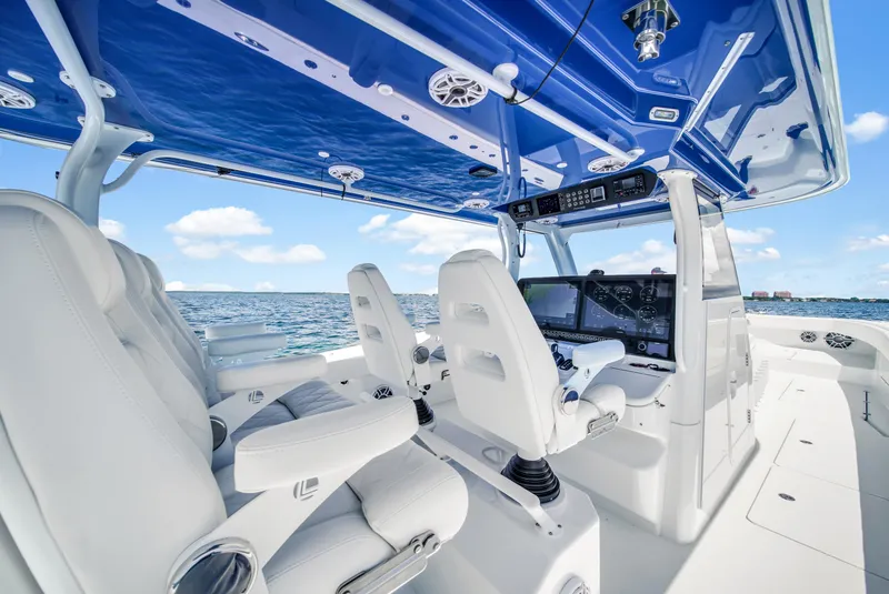 Slide: The Image of 2023 Freeman 47 boat interior with white seats and blue canopy on open water. - 39