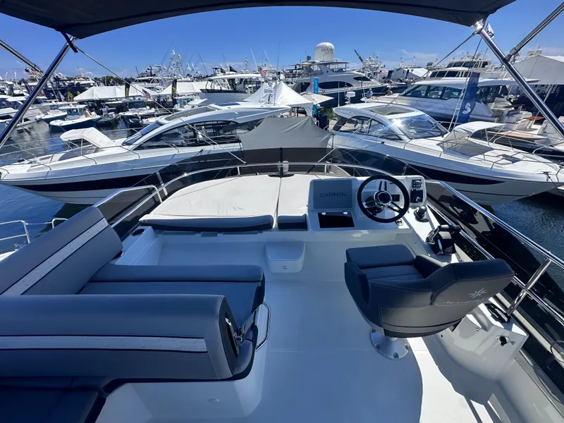 Slide: The Image of 2025 Jeanneau 1295 yacht cockpit with helm, docked among luxury boats. - 10
