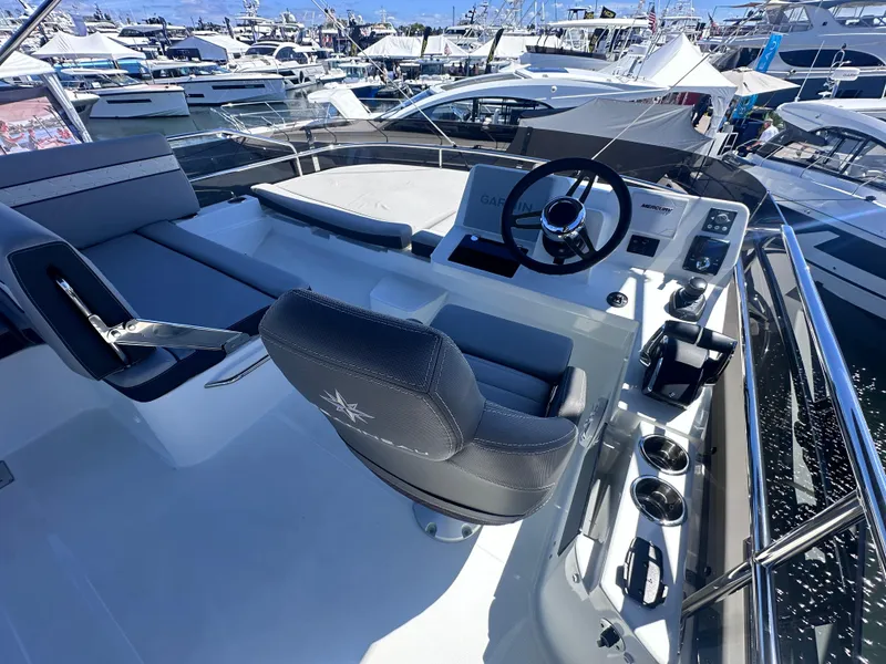 Slide: The Image of Flybridge of 2025 Jeanneau 1295 yacht with modern helm and seating, docked among other boats. - 11