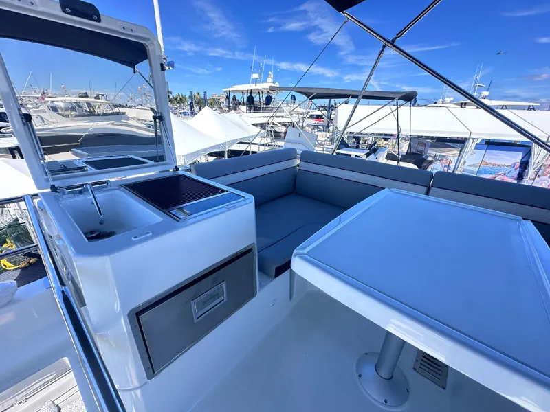 Slide: The Image of 2025 Jeanneau 1295 yacht deck with seating, table, and sink under a clear blue sky. - 12