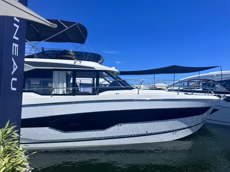 Slide: The Image of 2025 Jeanneau 1295 yacht docked under clear blue sky. - 2