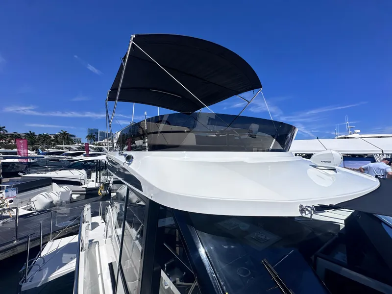 Slide: The Image of 2025 Jeanneau 1295 yacht with sleek design and canopy, docked under clear blue sky. - 4