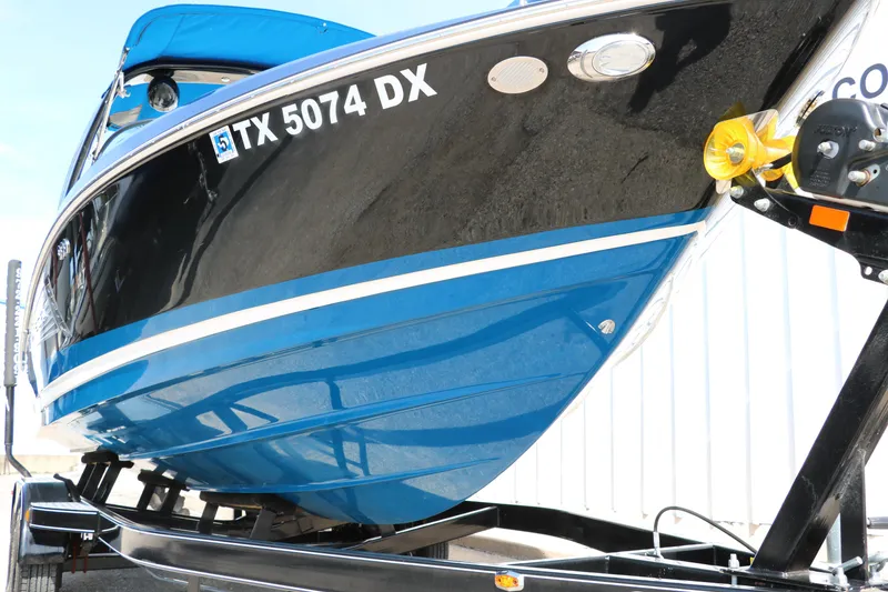 Slide: The Image of 2018 Regal 23 RX Surf boat on trailer, blue and black hull, side view. - 11
